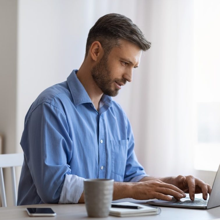 handsome male freelancer working on laptop at desk QNYNC7F e1622510476881